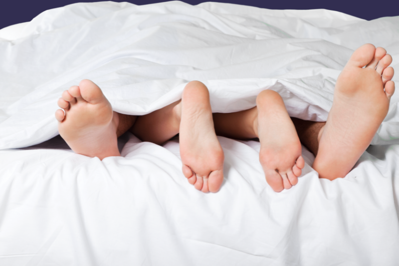 Duas pessoas debaixo dos lençóis em que só se vêm o pés.